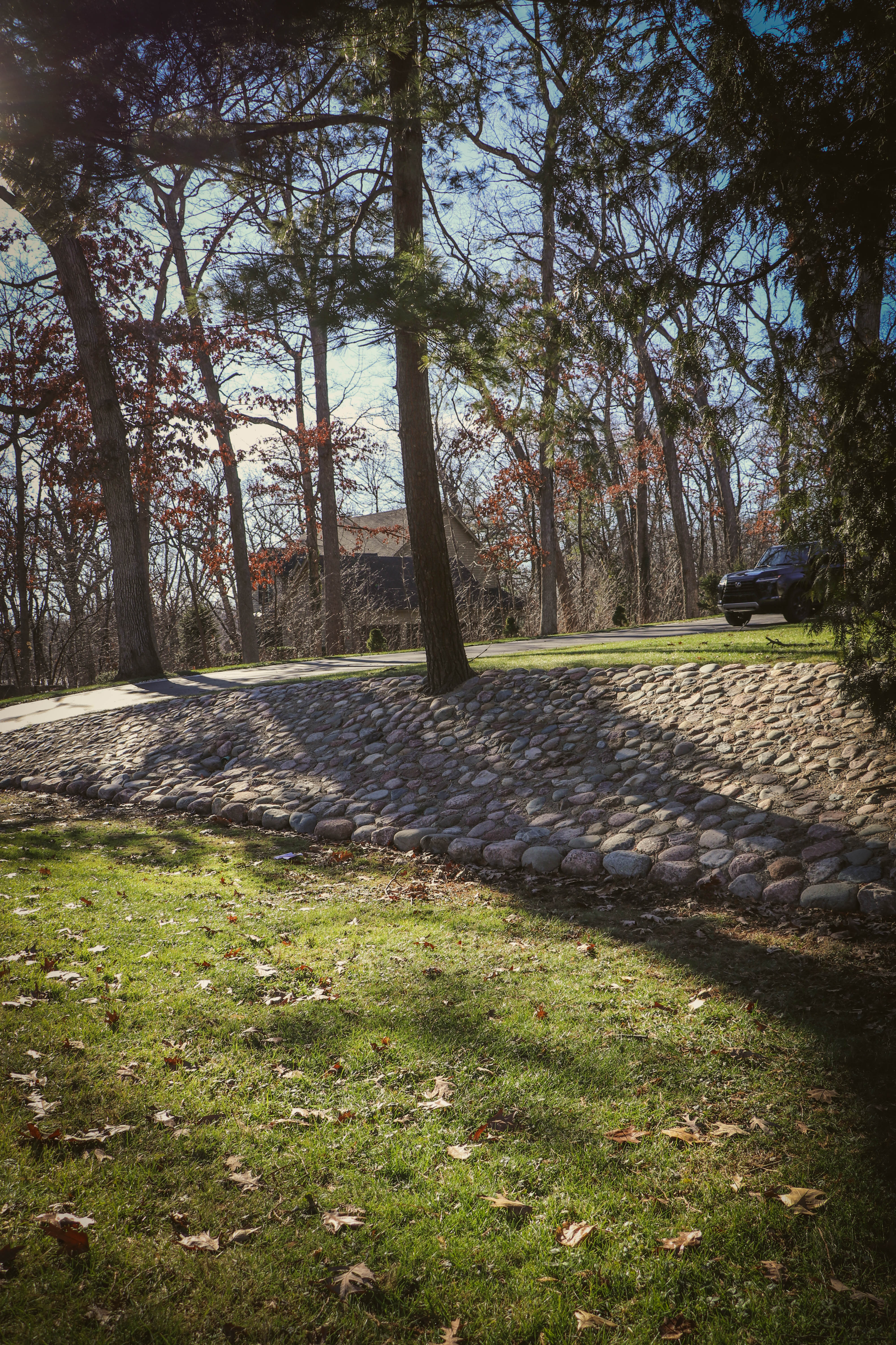 Cobble retaining slope and decorative rip-rap drainage feature with paver curb edge.