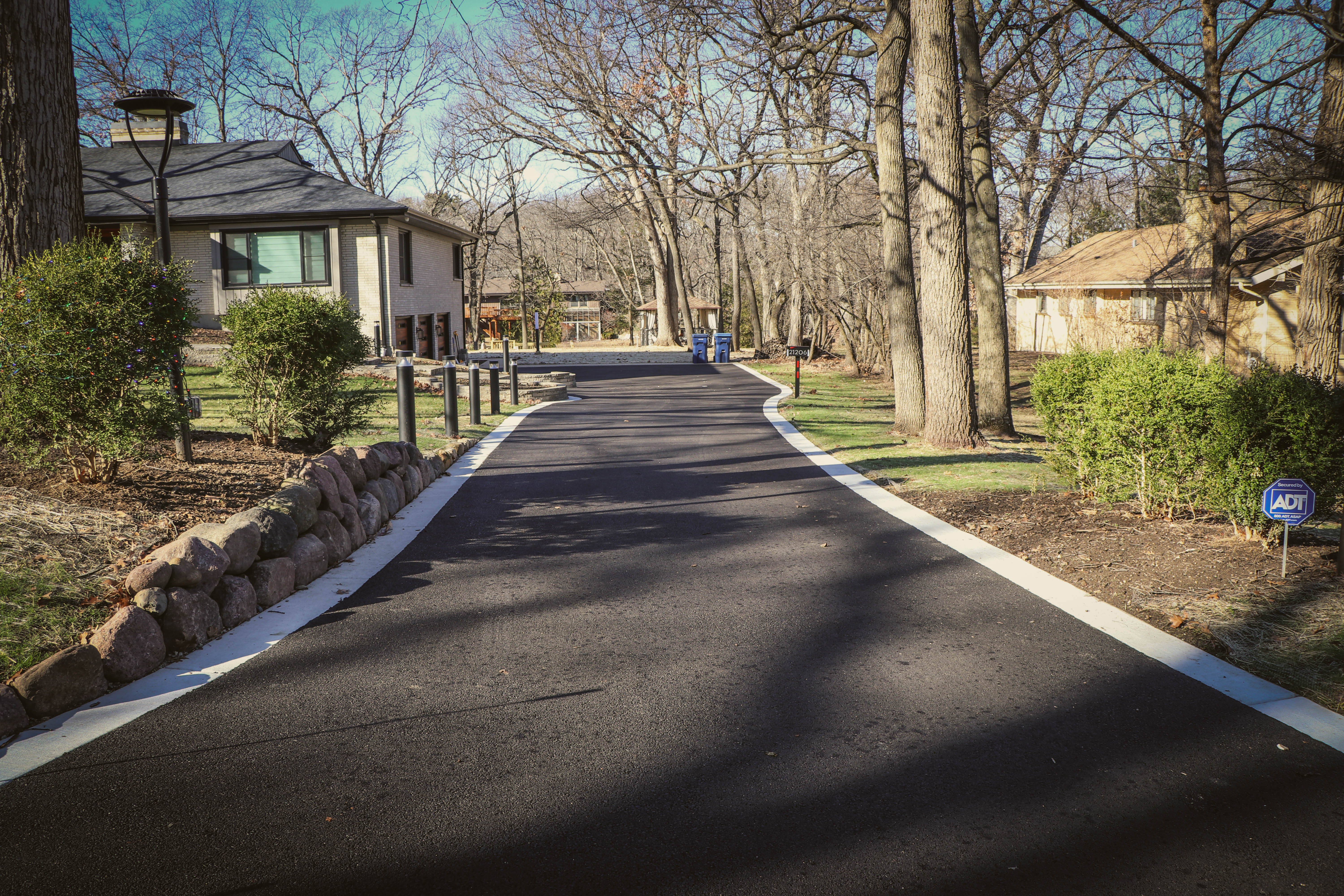 Finished paver driveway with stone bollards along a curved curb edge, Chicagoland residential property — installed by Exotic Pavers and Landscaping.